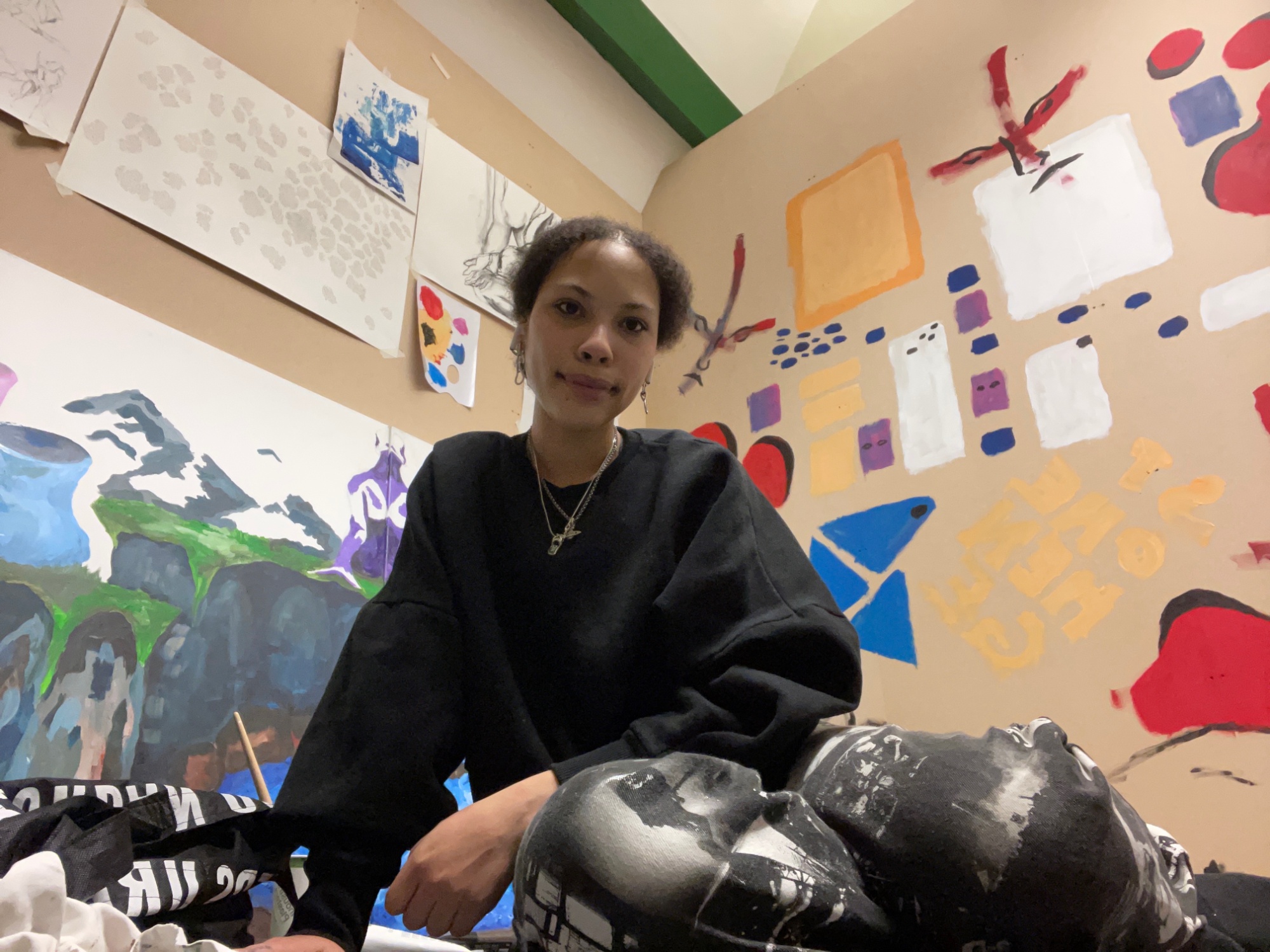 Girl sitting in a room with artwork covering the walls