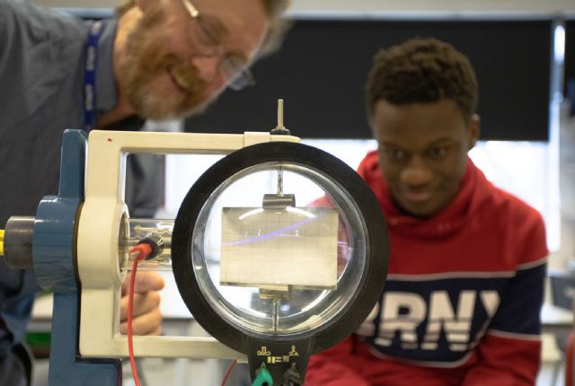 a male student and a male teacher  conducting a science experiment 